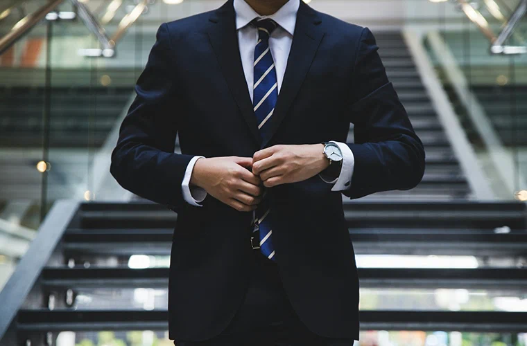一位穿着西装的人在办公楼梯脚下整理外套
